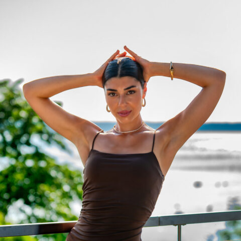 Naise portreefoto käed üleval poosis, must kleit, veekogu taustal