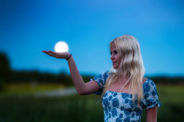 Naise portreefoto käes valgusallikaga, sinine õhtutaevas
