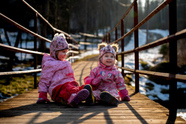 Kaks last istumas puidust sillal, kevadine jalutuskäik